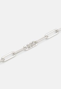 Snyggt armband i silver med avlånga länkar med polerad yta och en central länk präglad med "MK." Slät textur genom hela armbandet.