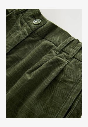 Pantalons en velours côtelé vert olive avec une surface texturée, comportant une fermeture à bouton et un design plissé. Le tissu présente un motif à carreaux subtil.