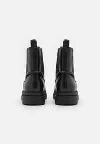 Svarta läderankelstövlar med elastiska sidopaneler, rund tå och dragtab bak. Slät finish, förstärkt gummisula, minimala stygn.