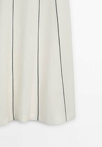 Cremefarbenes Kleid mit schwarzen vertikalen Streifen aus leichtem Stoff. Es zeichnet sich durch ein fließendes Design und einen leicht geschwungenen Saum aus.