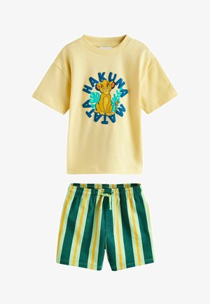 Maglietta gialla a maniche corte con Simba e la scritta "Hakuna Matata", abbinata a pantaloncini elasticizzati a righe verdi, gialle e azzurro chiaro.