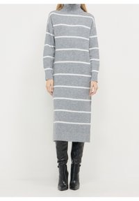 Abito maglione grigio a maniche lunghe con strisce orizzontali bianche, collo alto e taglio dritto, abbinato a stivali neri sopra il ginocchio.