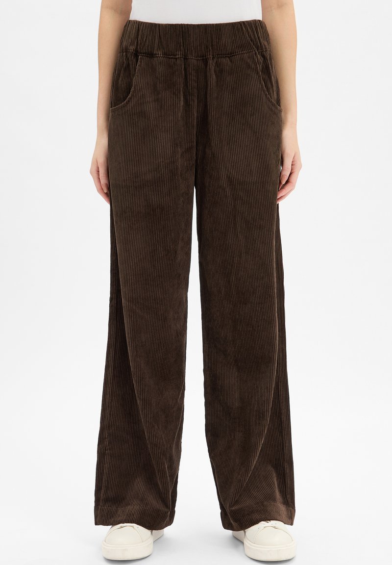 Brązowe szerokie spodnie z korka z elastycznym paskiem w talii i bocznymi kieszeniami. Miękka tekstura i pionowy prążkowany wzór na całej powierzchni.