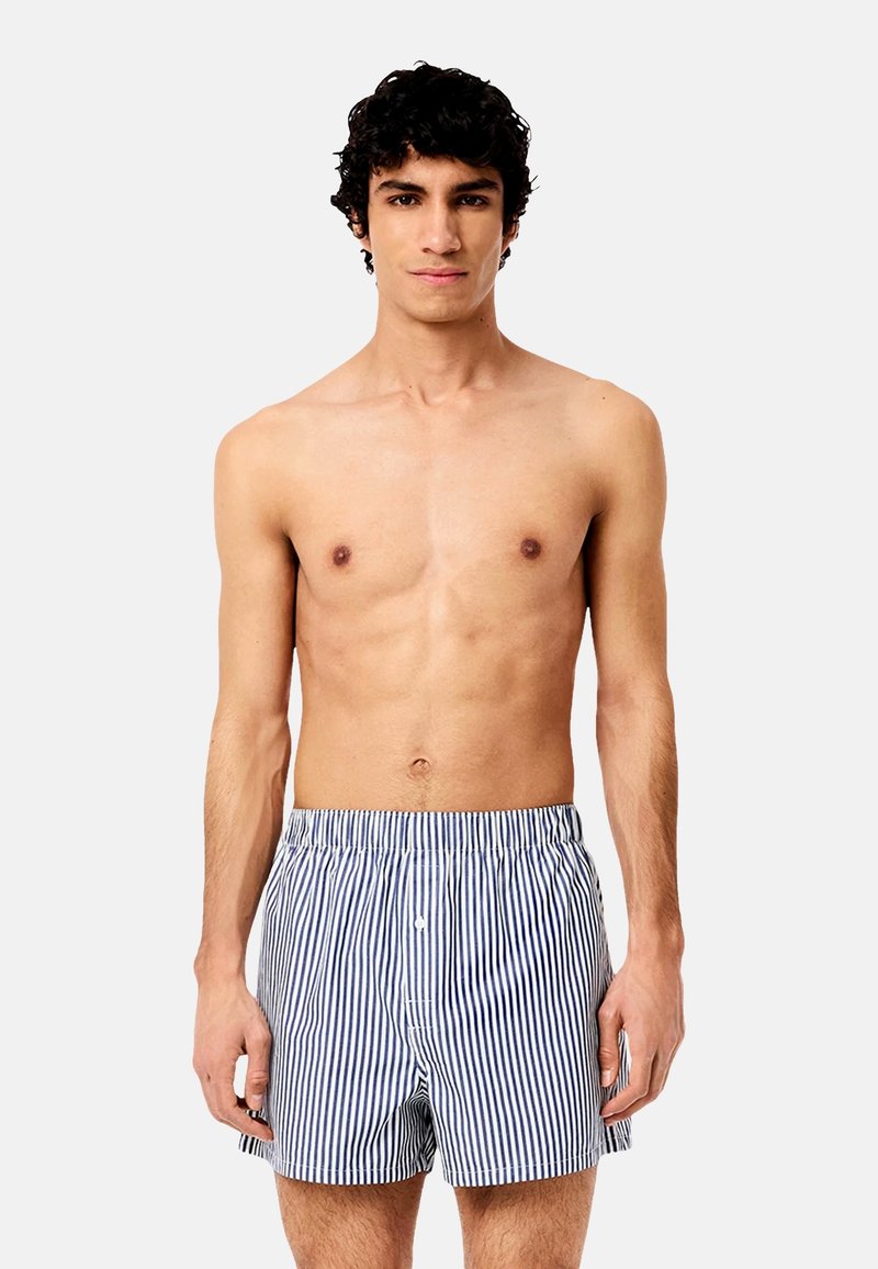 Striped cotton shorts in navy and white. Elastic waistband with a button closure, relaxed fit, and a soft texture.