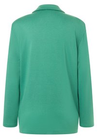 Grön långärmad polo med mjukt tyg, med klassisk krage och ren, minimalistisk design utan synliga logotyper eller mönster.