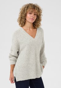 Světlé šedé oversized svetr s výstřihem do V, žebrovanými manžetami a bočními rozparky. Vyroben z měkké texturované tkaniny, poskytující uvolněný střih.