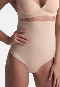 Mutanda modellante beige a vita alta, realizzata in un tessuto liscio e stretch. Presenta un design senza cuciture e una vita ampia per maggiore comfort e supporto.