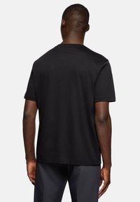 Black cotton short-sleeve t-shirt, crew neck design, smooth texture, with a relaxed fit, viewed from the back.