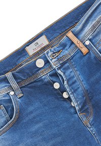 Jeans de mezclilla azul con un corte clásico, cinco bolsillos, costuras claras y una bragueta de botones. La etiqueta dice "LTB Blue Addicted."