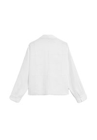 Veste blanche cropped en tissu texturé, dotée d'un col simple, de manches longues et d'un design à panneaux carrés dans le dos.