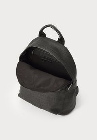 Sac à dos noir avec surface texturée, fermeture zippée et détails de logo. Intérieur spacieux avec une poche zippée à l'avant, forme arrondie et poignée sur le dessus.