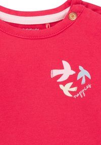 Rotes Baumwollhemd mit drei stilisierten Vogelgrafiken in Pastellfarben und einem kleinen Blumenknopf am Ausschnitt.