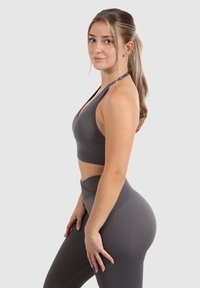 Grijze sportbeha en hooggehakte leggings, gemaakt van een gladde, elastische stof. Heeft een halterhals en geribbelde taillebanddetails.