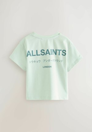 Kergelt piparmündiroheline puuvillane T-särk lühikeste varrukatega, millel on seljal silmatorkav sinine tekst: "ALLSAINTS" ja "LONDON".