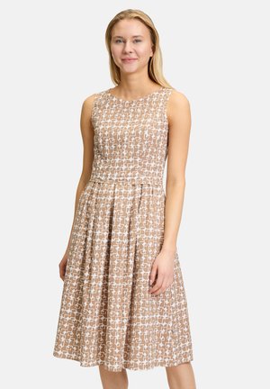 Beiges Kleid mit einem geometrischen weißen Muster. Ärmelloses Design, taillierte Passform und schwingender Rock. Glattes Material mit einem dezenten Glanz.