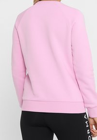 Růžová mikina se hladkým povrchem, raglánovými rukávy a žebrovaným lemem. Výrazná svým jednoduchým a neformálním designem.