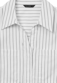 Chemise blanche à col rabattu avec des rayures verticales noires, dotée de deux poches avant et d'un design à boutonnière. Texture du tissu lisse. Étiquette de la marque visible.