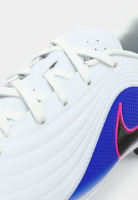 Λευκό αθλητικό παπούτσι με λευκές κορδόνες, μπλε υφασμάτινη πλευρική επιφάνεια και μαύρο έμβλημα Nike περιγραμμένο σε ροζ.