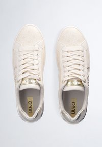 Liu Jo beige sneakers med præget mønster, hvide snørebånd, gyldne detaljer og en tekstureret sål. Rund tå og polstret indvendig.