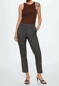 Top senza maniche marrone, pantaloni grigi a fantasia con una vestibilità slim, tasche laterali e sandali neri con cinturini. Tessuto liscio e design su misura.