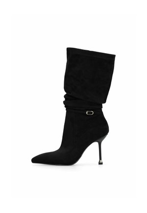 Stivaletti neri in suede con un'asta morbida, punta affusolata e tacco a stiletto sottile con un accento metallico vicino alla base.
