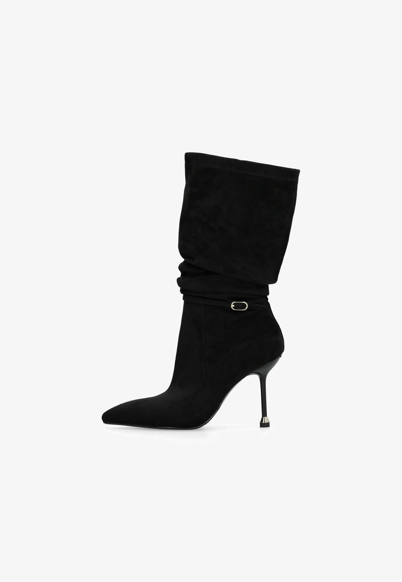 Stivaletti neri in suede con un'asta morbida, punta affusolata e tacco a stiletto sottile con un accento metallico vicino alla base.