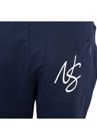 Granatowe dresy wykonane z miękkiej bawełny, z białym logo na tylnej kieszeni i casualowym fasonem z przeszyciami.