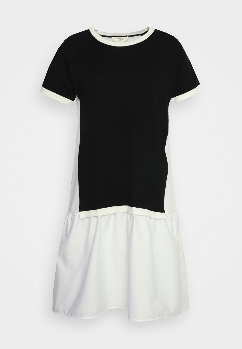 Robe en noir et blanc avec un haut en coton noir, manches courtes, et une jupe blanche à volants. Accentuée par un col contrastant.