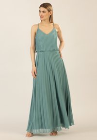 Plissé maxi-jurk in teal, gemaakt van lichtgewicht stof. Heeft een V-hals, dunne verstelbare bandjes en een vlotte silhouet.
