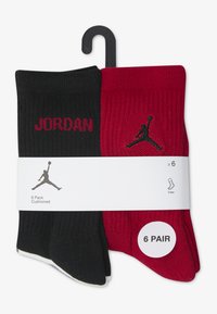 Skarpety typu crew w kolorach czarnym i czerwonym, o prążkowanej fakturze, z napisem „JORDAN” w czerwonym kolorze na czarnym tle oraz czarnym logo na czerwonym, sprzedawane w opakowaniach po 6 par.