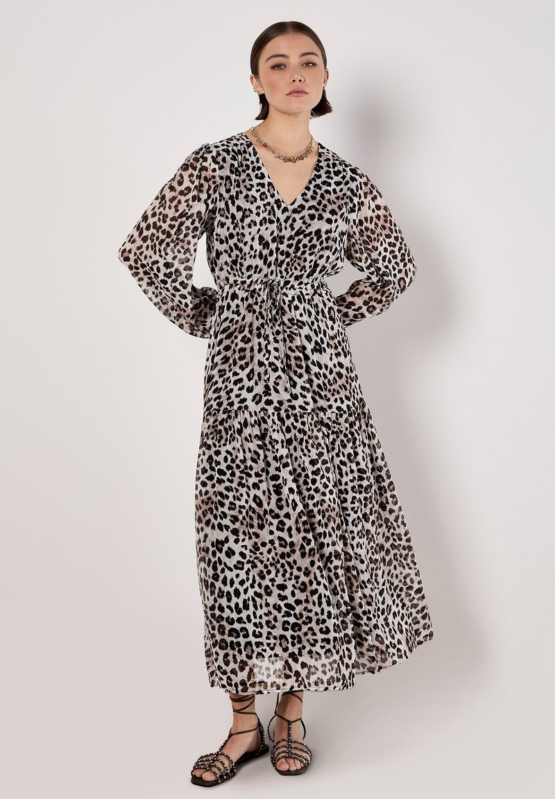 Maxikleid aus durchscheinendem Stoff mit Leopardenmuster, V-Ausschnitt, elastischem Bund und langen, fließenden Ärmeln. Kombiniert mit Riemchensandalen.