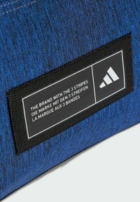 Blue fabric with a textured finish, featuring a black rectangular label with white text and a logo in the corner.