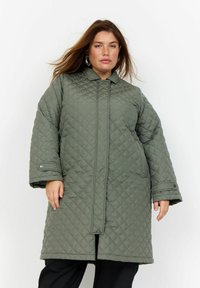 Cappotto esterno verde trapuntato con alta collana, maniche lunghe e bottoni frontali. Presenta una vestibilità ampia e un motivo a rombi testurizzato.