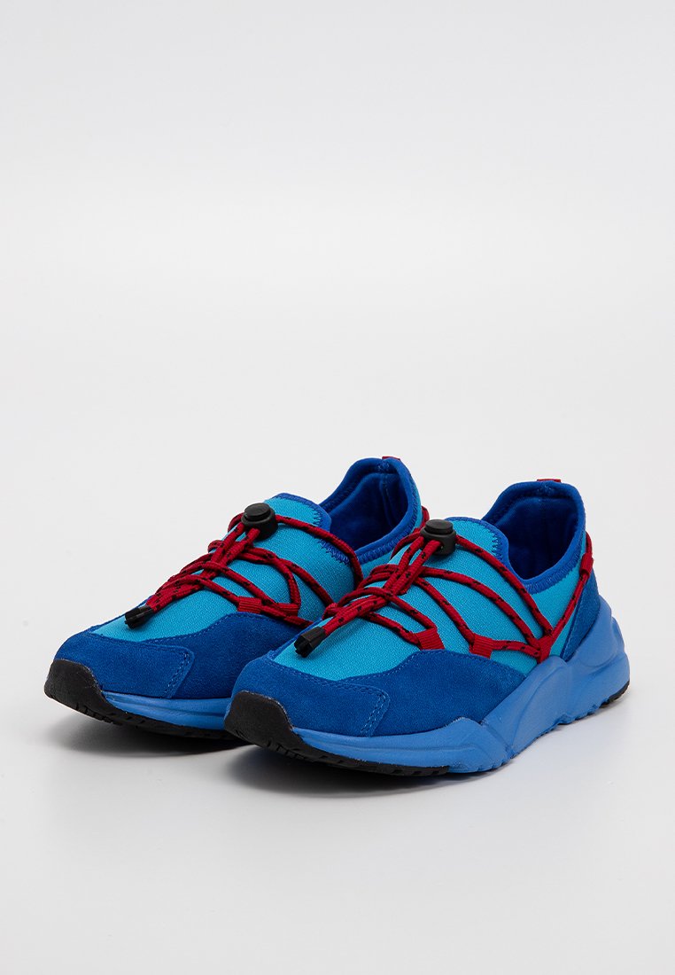 Une paire de chaussures de sport bleues avec des lacets élastiques rouges sans nœud et des fermetures à bascule noires sur fond blanc.