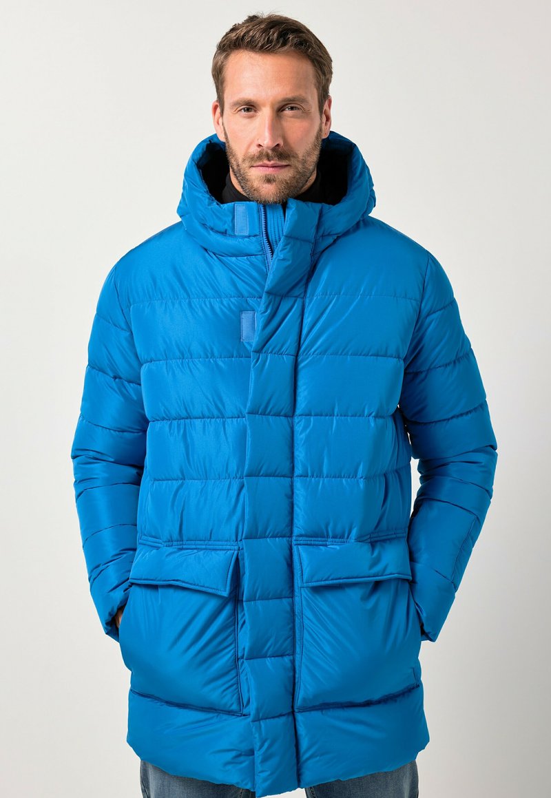 Giacca a vento blu con cappuccio, caratterizzata da sezioni trapuntate orizzontali, chiusura frontale con zip e due ampie tasche frontali.