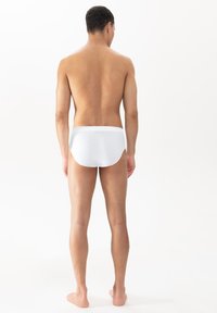 Weiße Baumwollunterwäsche mit einem strukturierten Muster, ausgestattet mit einem weichen, elastischen Bündchen, auf einem männlichen Model von hinten präsentiert.