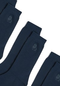 Calzini di cotone blu navy con polsini a coste e un sottile dettaglio di logo ricamato. Quattro paia disposti per la visualizzazione, mostrando un design uniforme.