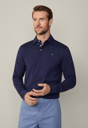 Navyblaues Langarm-Polohemd mit Kragen, drei Knopfverschluss und dezentem Logostick. Das Material wirkt glatt und leicht.