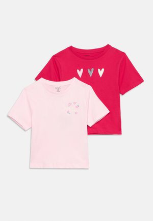Zwei kurzärmelige Kinder-T-Shirts, eines hellrosa mit kleinem Blumenmuster, eines knallpink mit drei Herzmotiven auf der Brust.