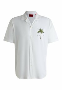 Korte mouwen witte shirt van gladde stof, met een groene palmboomafbeelding op de linkerborst en knopen langs de voorkant.