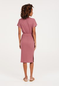 Vestido midi color frambuesa hecho de una tela texturizada, con mangas cortas, cintura ceñida con cinturón y aberturas laterales.