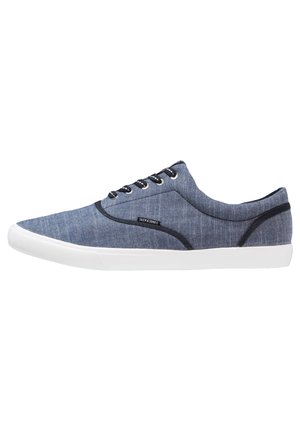 Zapatilla deportiva azul de caña baja con suela blanca, ribete negro, cordones negros y etiqueta "Jack & Jones" en el lateral.