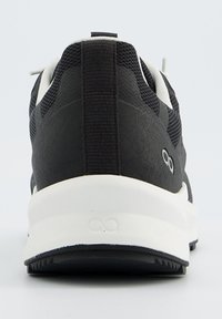 Chaussure de sport noire avec une tige texturée, des accents en maille et une semelle intermédiaire blanche. Équipée d'une anse au talon et d'un branding discret.