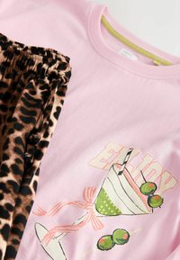 Chemise rose avec inscription « ENJOY » et illustration de cocktail, associée à un pantalon imprimé léopard avec taille élastique et cordons.
