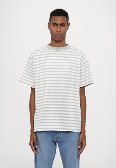 Striped t-shirt in light gray and white, short sleeves, round neckline, relaxed fit, with a tag on the left side near the hem.