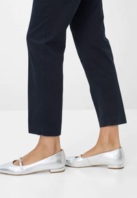 Scarpe balletto piatte in metallo argentato, con punta tonda e un piccolo dettaglio a fibbia. Abbinato a pantaloni sartoriali blu navale. Texture liscia, tacco basso.