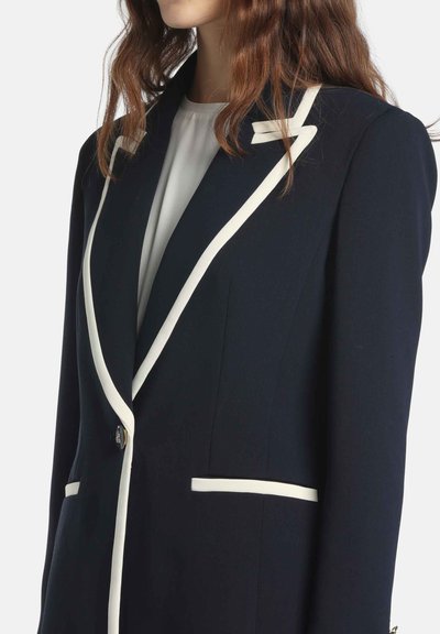 Tmavomodrý blejzer s bielym lemovaním, štruktúrovaným dizajnom, zapínaním na jeden gombík a klopov ými vreckami. Textúrovaná tkanina s elegantným, priliehavým strihom.