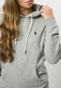 Grå huvtröja i mjukt bomullsblandning, med känguruficka, dragsko huva och broderad logotyp på bröstet.