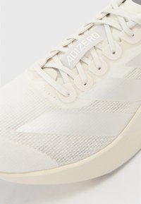 Lightweight running shoe with a white mesh upper, minimalistic design, textured pattern, and a prominent "ADIZERO" logo on the tongue.