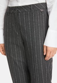 Gray wool trousers with white pinstripe pattern, featuring a flat front, belt loops, and a small logo detail on the waistband.